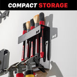 A black wall-mounted brush holder labeled with a large letter M cutout, holding several red-handled brushes. The image includes a top banner reading 'COMPACT STORAGE' H06C Wall Mount Tool Holder