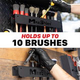 A black MaxShine brush holder mounted on a diamond-plate wall and wood surface, with gloved hands holding and demonstrating brush storage. Large text across the center reads 'HOLDS UP TO 10 BRUSHES'. H06A H06D Car Detailing Brush Holder