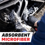 A close-up action shot of a person using a black and white microfiber cleaning cloth on a car wheel well, covered in white cleaning foam. The text 'ABSORBENT MICROFIBER' is overlaid at the bottom. 112000WS Microfiber Wheel Scrubbing Belt - 2 Pack