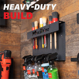 A black MaxShine heavy-duty wall-mounted brush holder with several detailing brushes and spray bottles attached, shown against a rustic wood plank wall. Large text at the top reads 'HEAVY-DUTY BUILD'. H06 Wall Mount Tool Holder