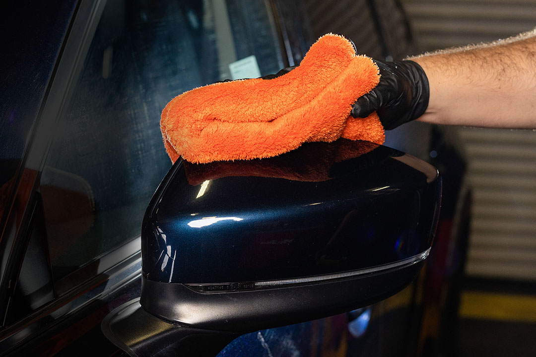1000GSM Little Orange Microfiber Drying Towels on Dark Blue Car Side Mirror
